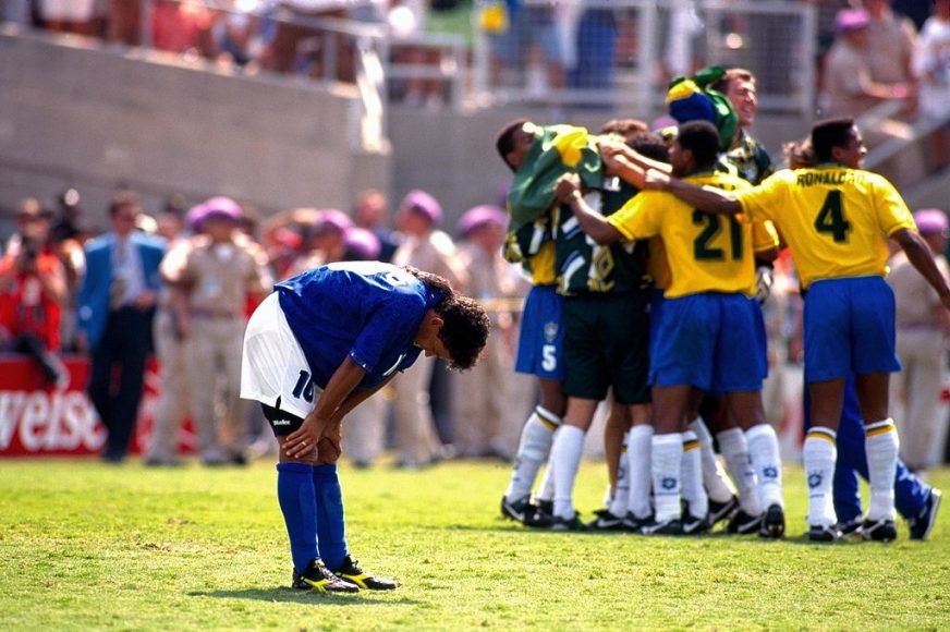 Roberto Baggio has his hands on his knees in despair as the Brazilian team celebrate his missed penalty which won them the world cup